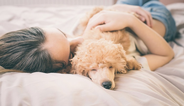 A Woman Cuddling with Her Dog in Bed